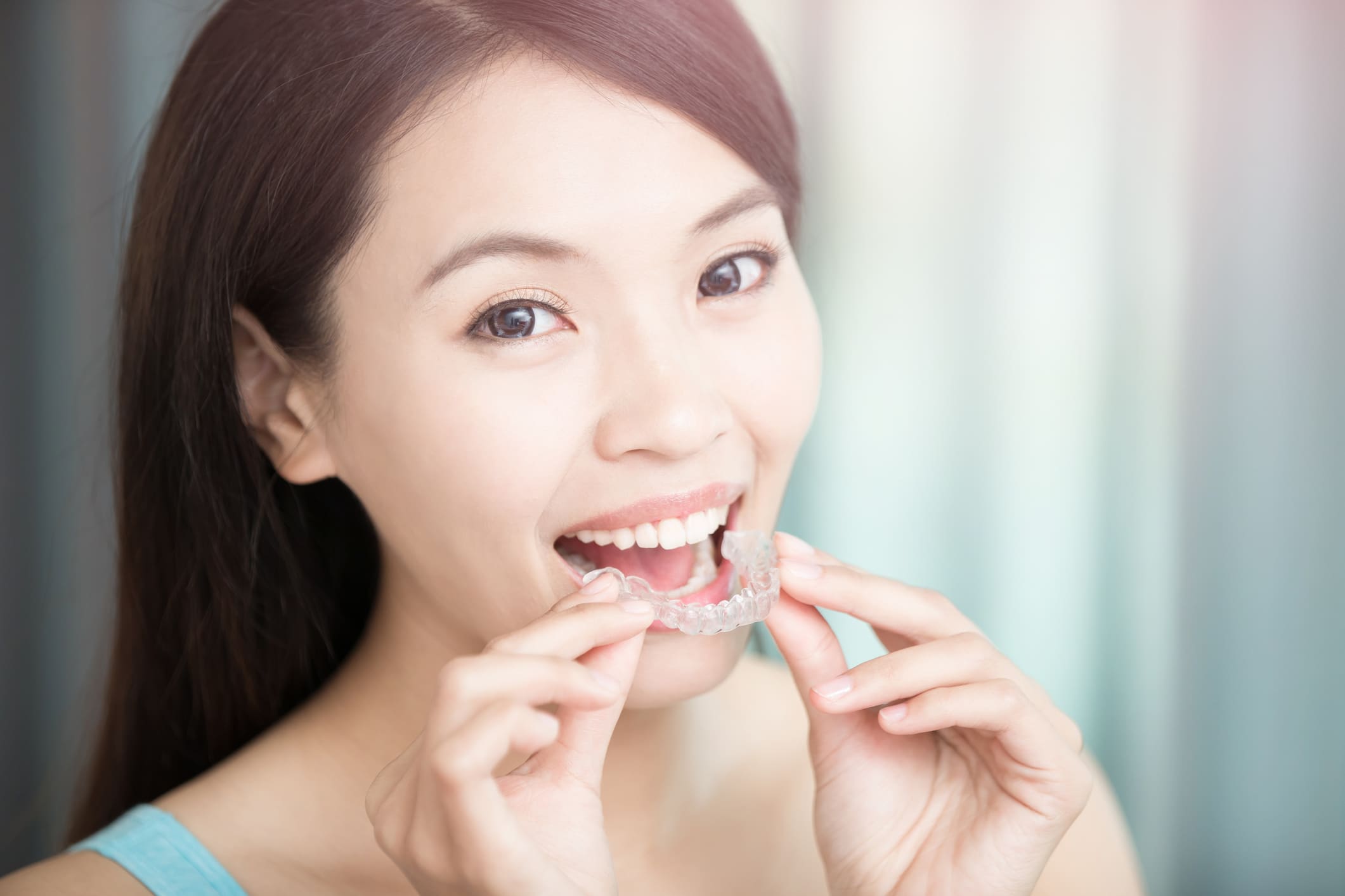 a-person-smiling-while-putting-in-dental-aligners