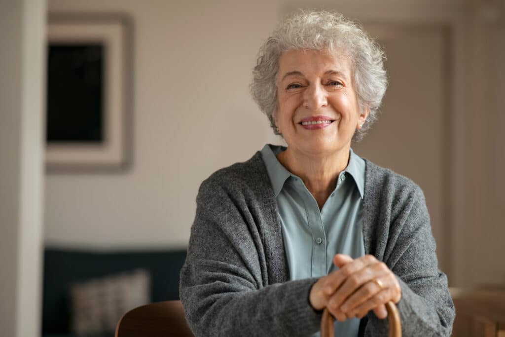 Portrait,Of,Smiling,Mature,Woman,Holding,Walking,Stick,And,Sitting