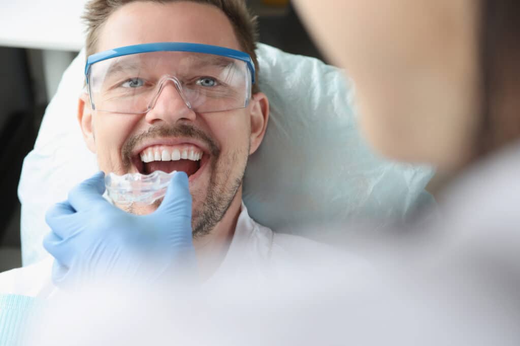 Doctor,Tries,On,Plastic,Mouthguard,For,Young,Smiling,Man,To