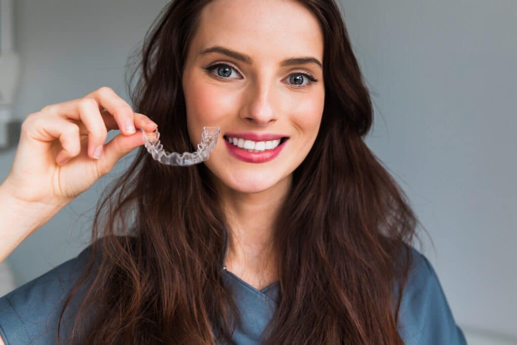 Young,Beautiful,Woman,Holding,Dental,Aligner,Orthodontic,To,Tee